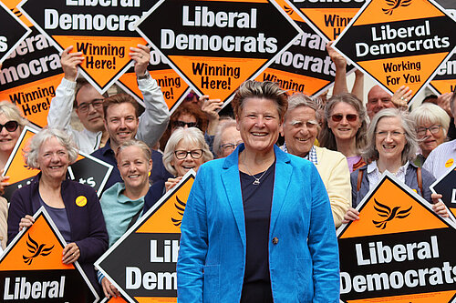 Sarah Dyke in front of crowd holding Liberal Democrat signs