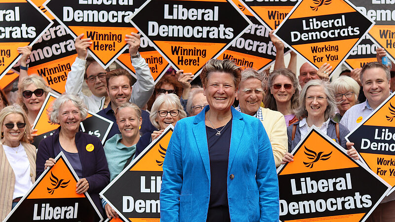 Sarah Dyke in front of crowd holding Liberal Democrat signs