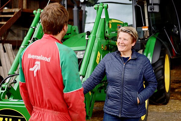 Sarah Dyke talks to a farm worker in front of a tractor